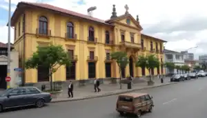 a yellow building with a cross on top and a car on the street